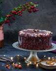 An ice cream cake coated in dark chocolate, and decorated with hazelnuts, against a festive background.