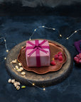 A desserts shaped like a gift, coated in pink chocolate with a bow.