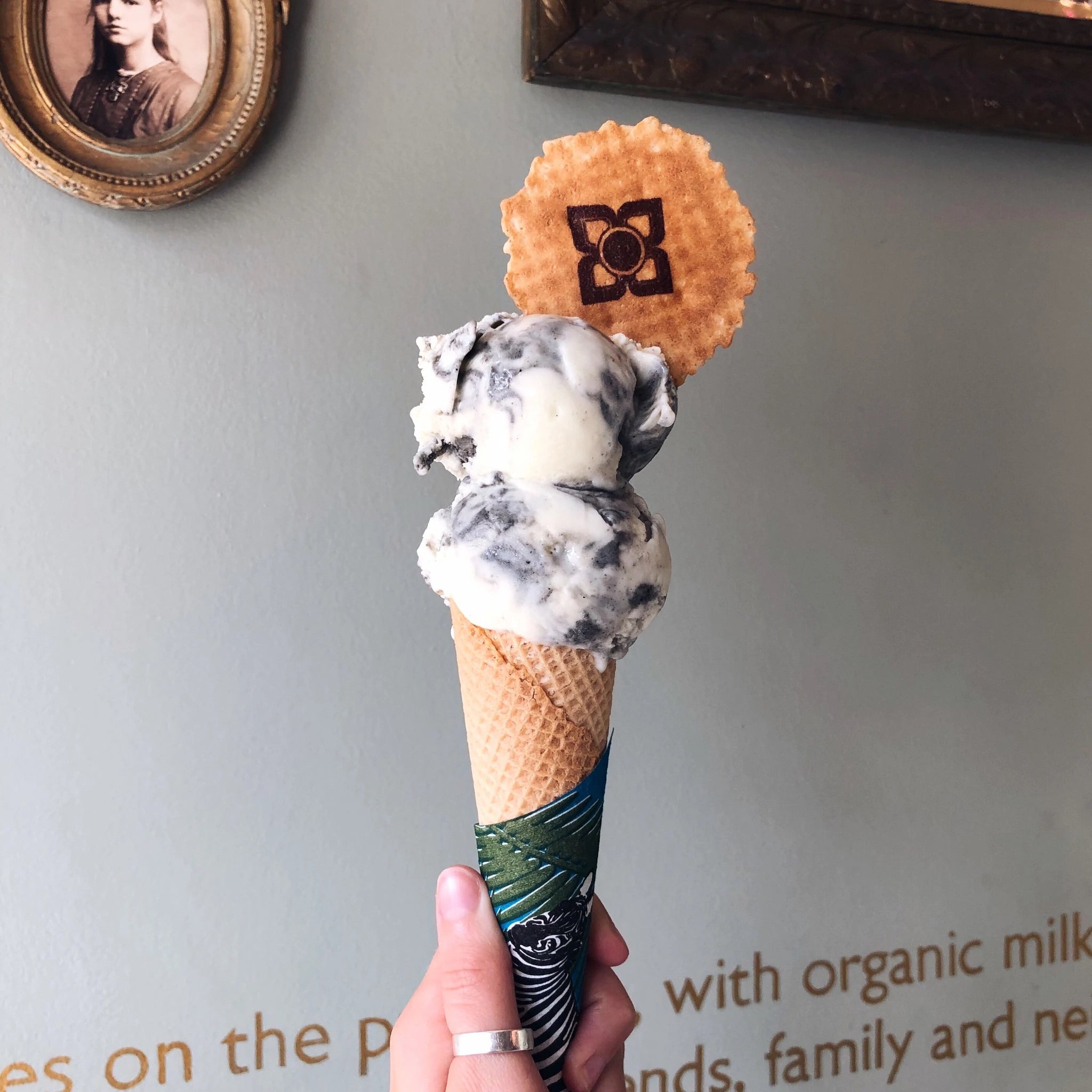Two scoops of black sesame ice cream on a cone with a wafer