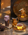 Hot chocolate in a golden cup, next to a glass jar full of chocolate callets