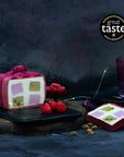 A desserts shaped like a gift, coated in pink chocolate with a bow, sliced to reveal a geometric pattern.