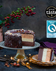 An ice cream cake coated in dark chocolate, cut through to reveal layers of different colours, against a festive background.