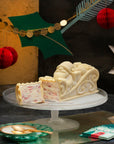 An ice cream cake coated in white chocolate, shaped like Santa on his sleigh, on a stand against a festive background.