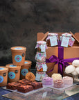Assorted treats including ice cream, brownies,sauces and toppings and ice cream flowers with a hamper box wrapped with a purple ribbon
