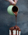 Belgian Chocolate sauce being poured over a slice of ice cream cake