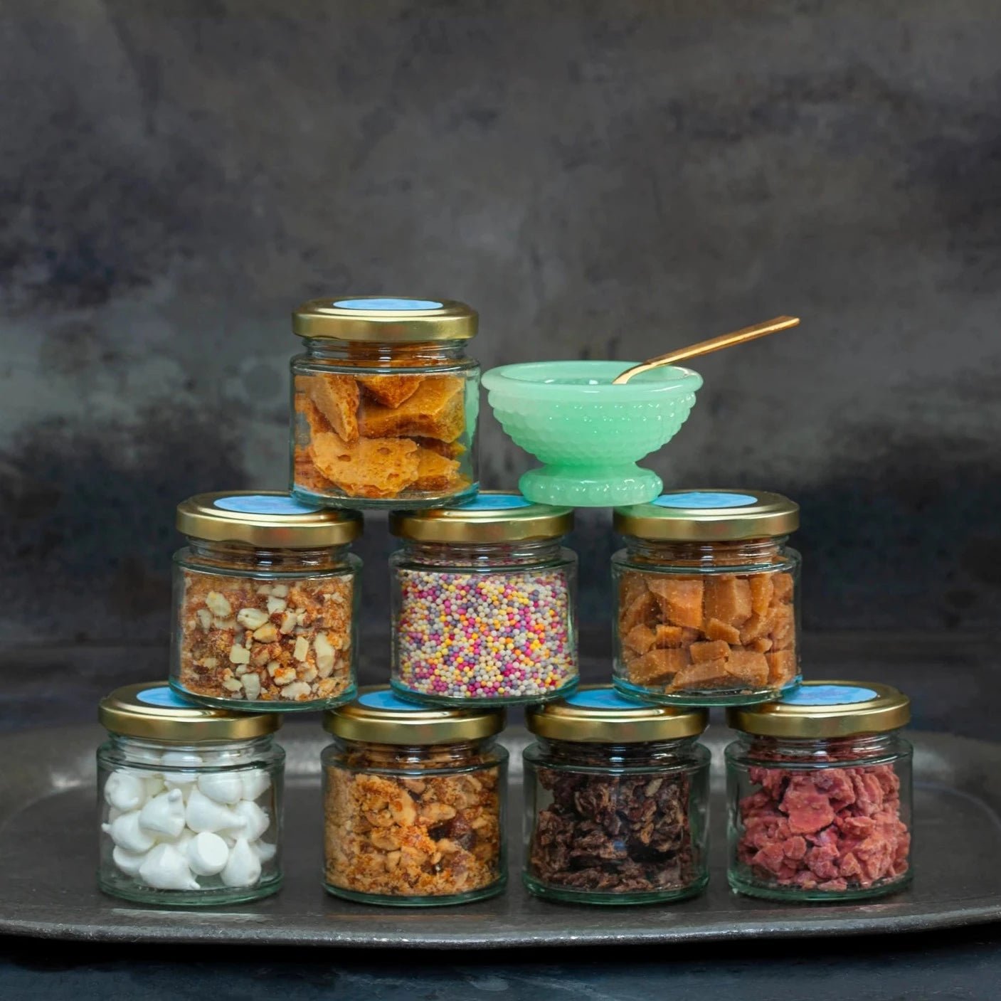 A stack of small glass jars, each containing a different topping