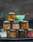 A stack of small glass jars, each containing a different topping