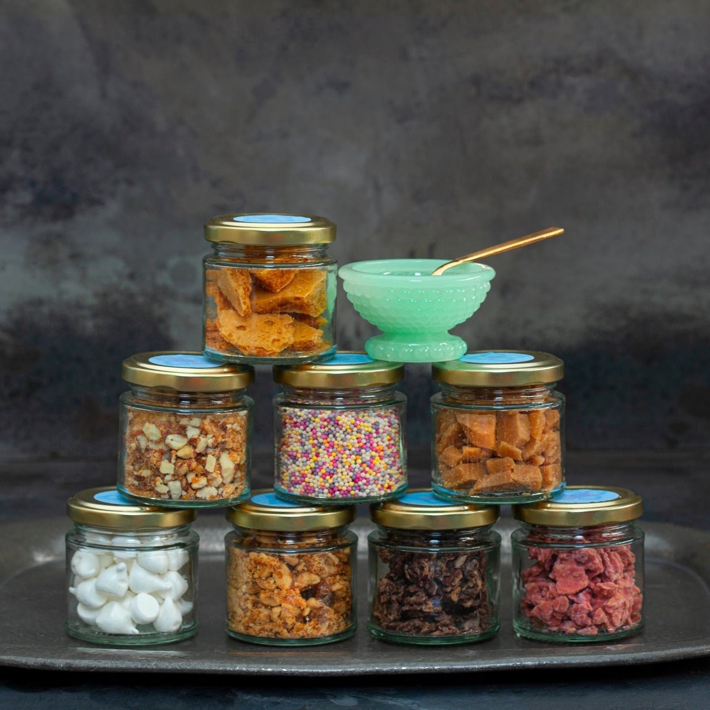 A stack of glass jars filled with different colourful toppings.