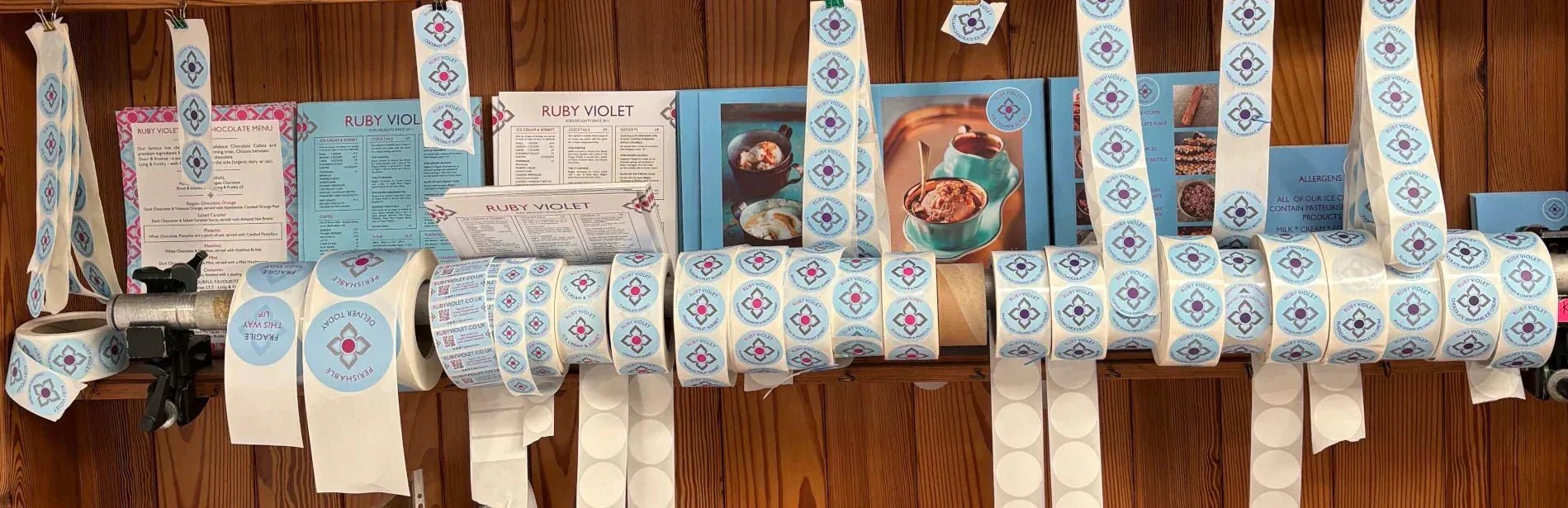 Ruby Violet stickers used to package orders against a wooden shelf