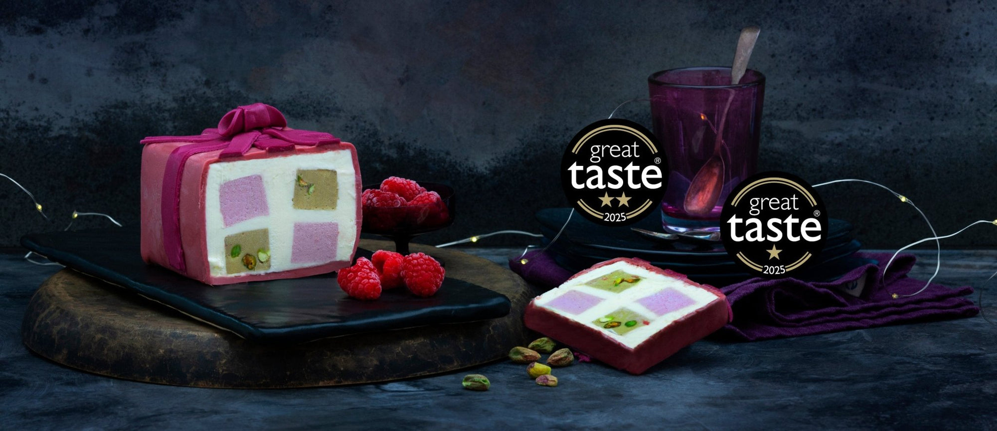 A pink ice cream cake with the great taste awards 2025 logos on a dark background
