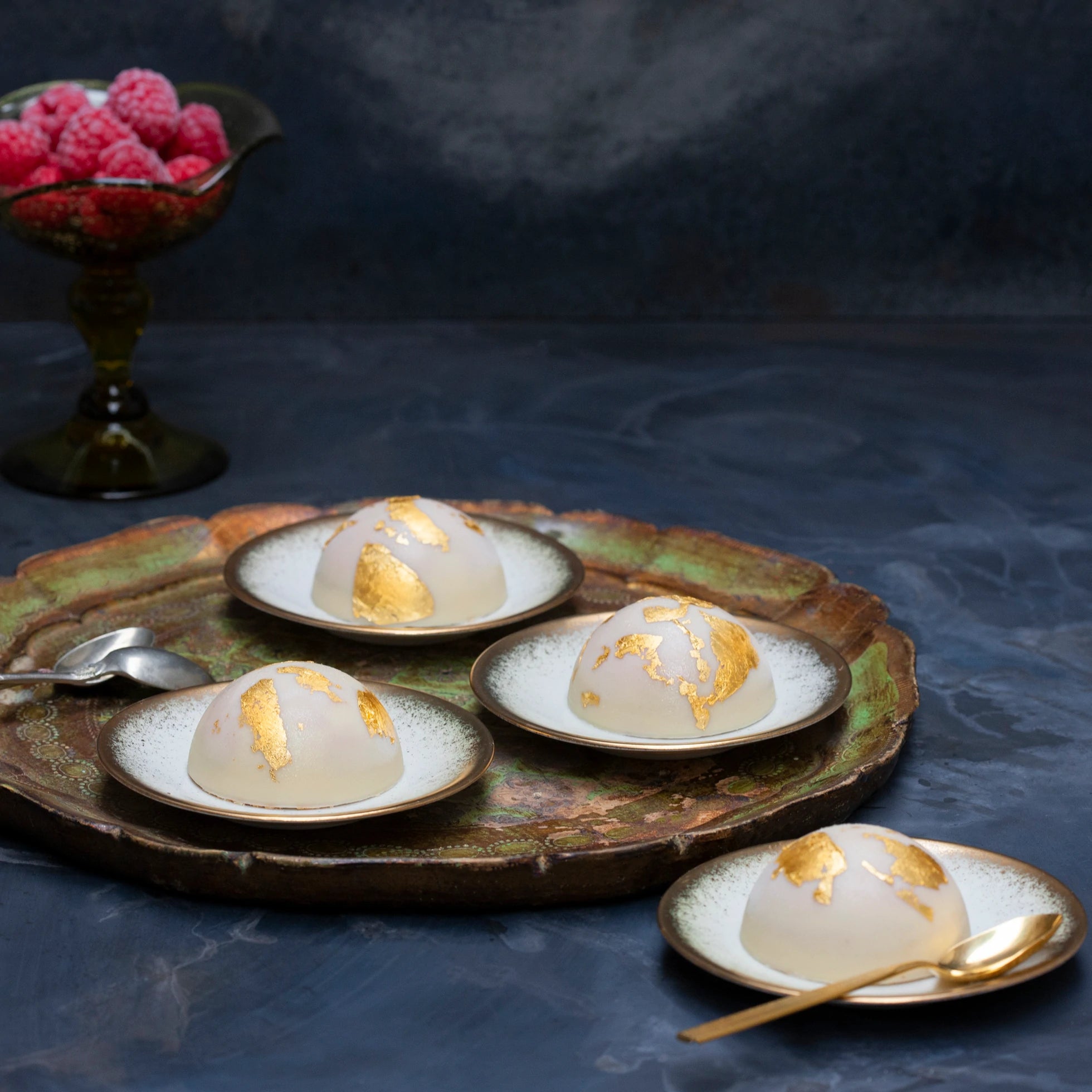 Mini vegan raspberry bombes on a tray decorated with gold