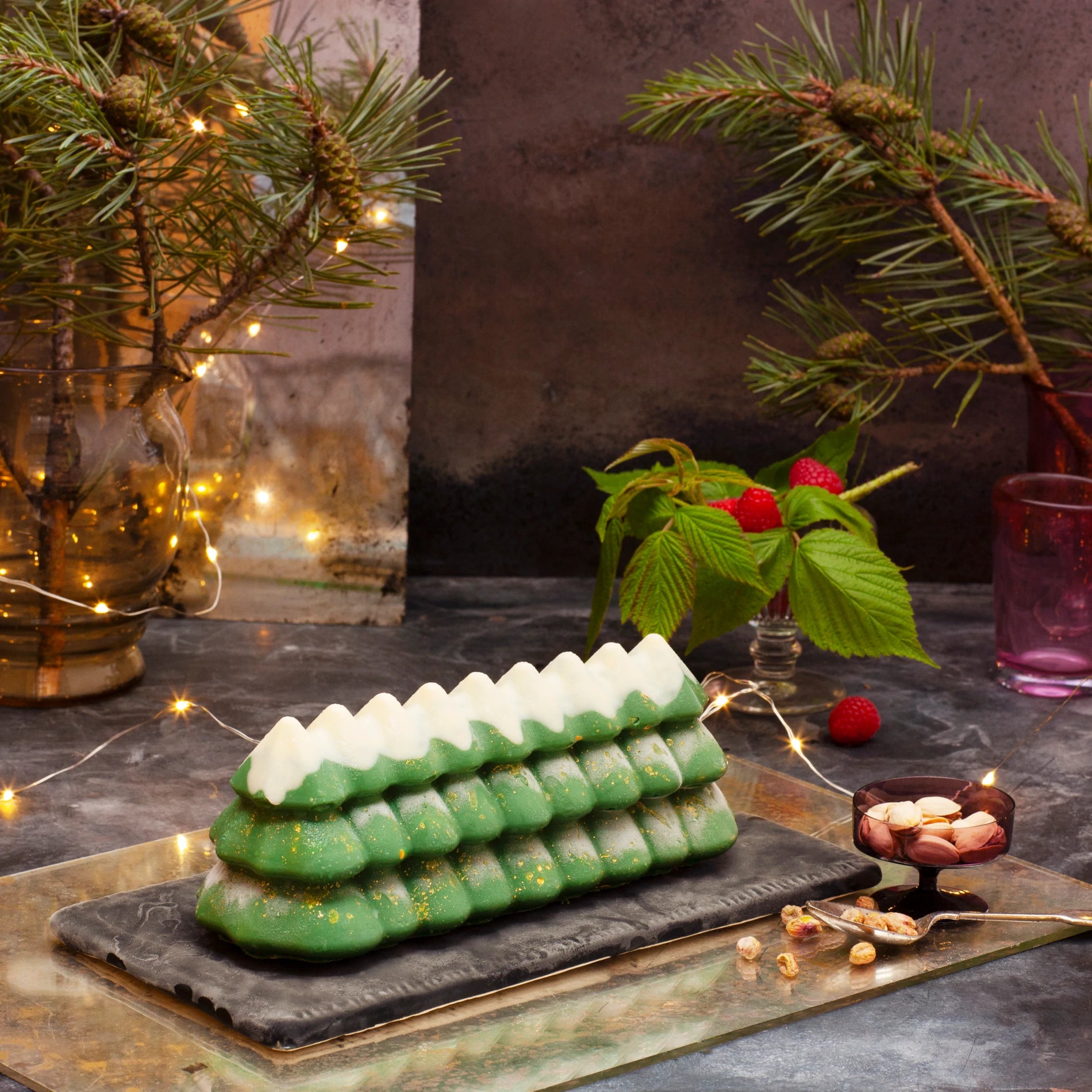 Christmas tree shaped dessert on a dark surface with festive decorations in the background