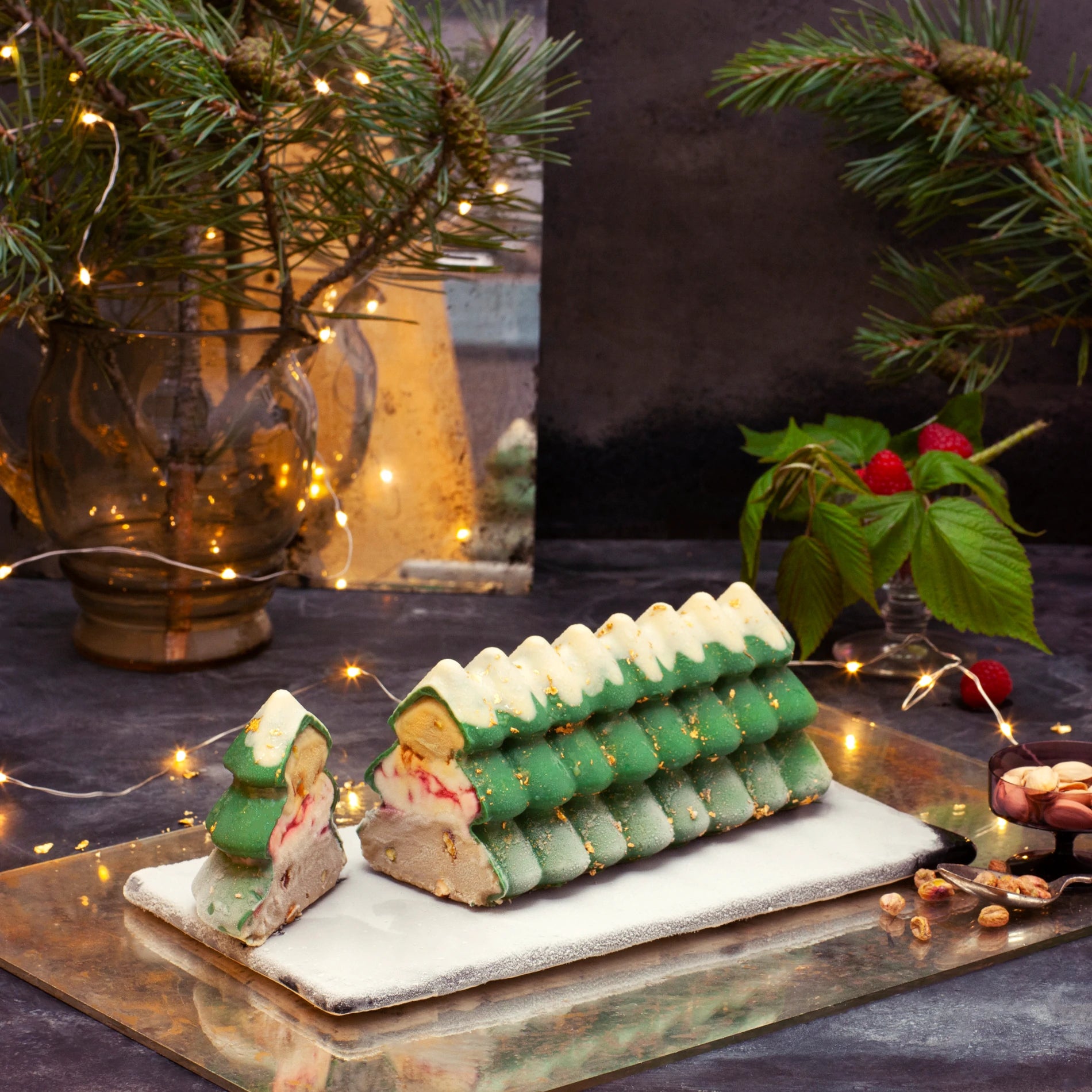 Christmas tree-shaped dessert on a marble slab with festive decorations in the background