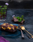 A gold mint chocolate bar on a tray with fresh mint and dark chocolate