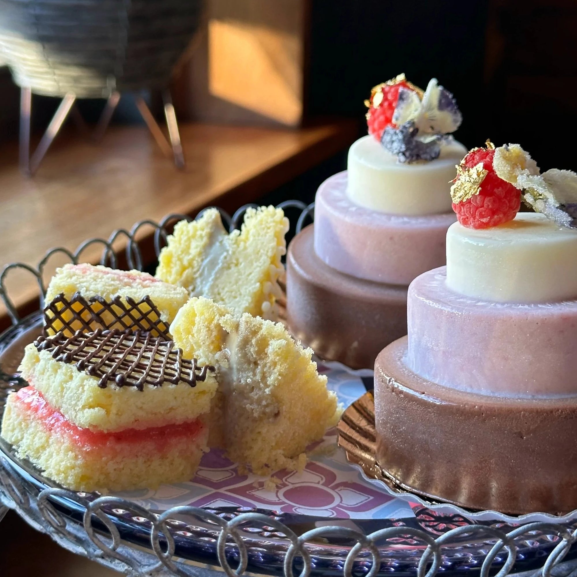 Sweet sandwiches and tiered ice cream cakes on a tray decorated with gold