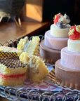 Sweet sandwiches and tiered ice cream cakes on a tray decorated with gold