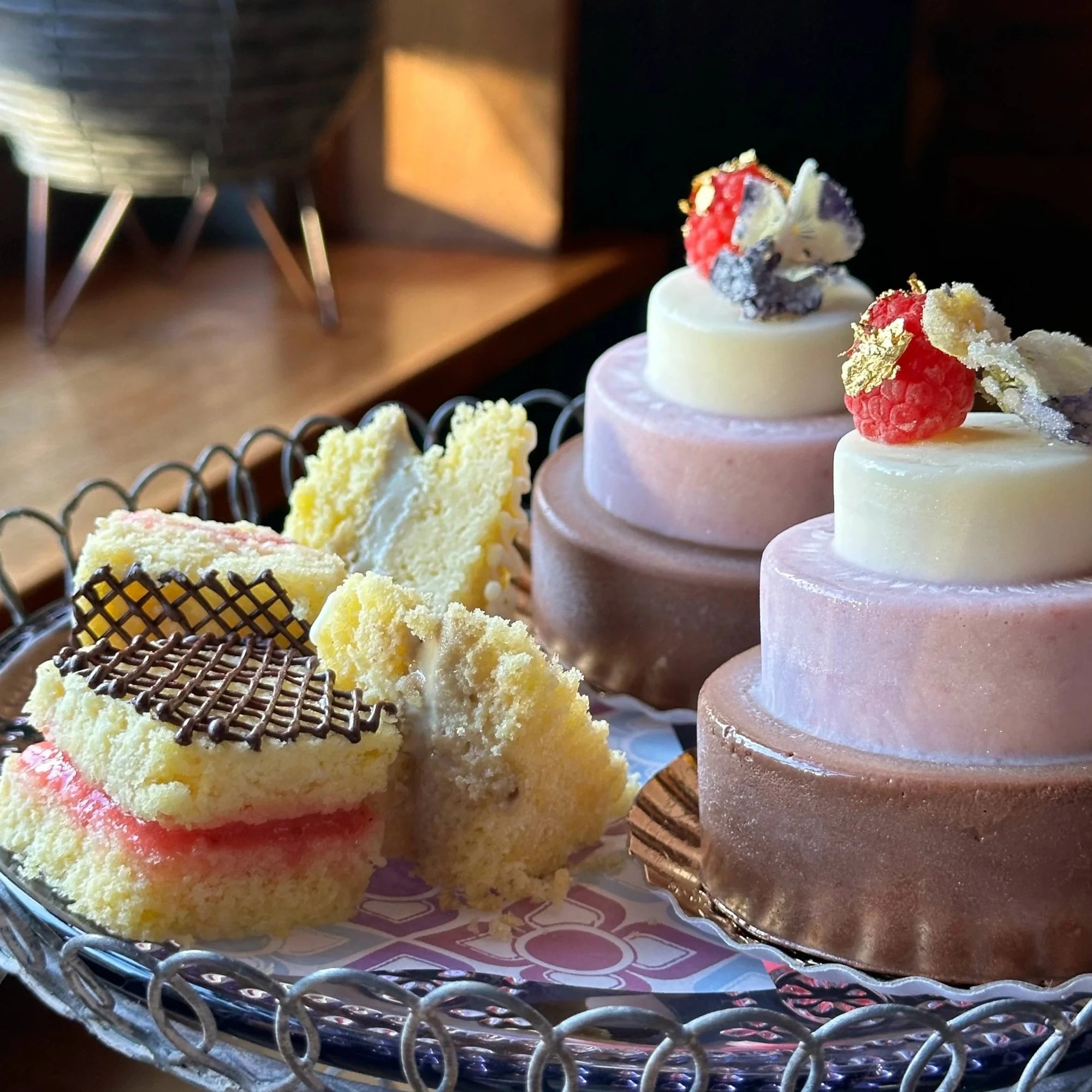 Tiered mini ice cream cakes decorated with berries and gold and mini sponge ice cream sandwiches on a tray