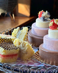 Tiered mini ice cream cakes decorated with berries and gold and mini sponge ice cream sandwiches on a tray