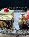 Square ice cream cakes coated in chocolate next to 4 ice cream chocolates and a sorbet on a stick