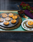 Handmade Frangipane topped minced pies on a tray, topped with icing sugar