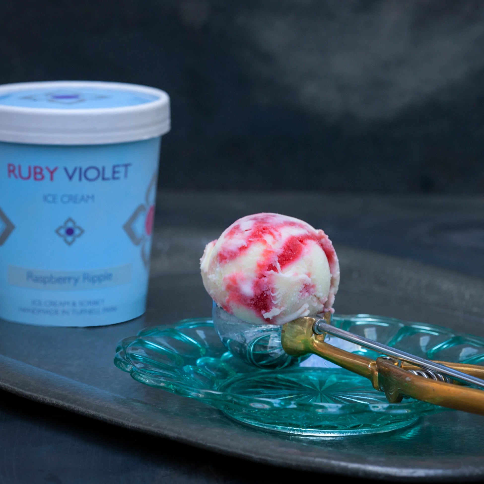 A scoop of raspberry ripple with a tub in the background