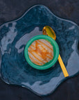 Scoop of banana caramel ice cream on a blue plate with a golden spoon