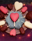 Heart-shaped and regular ice creams on sticks on a plate with a purple background and string lights.