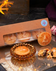 Box of frangipane mince pies with a window, one is on a glass plate, and another broken open on a reflective surface.
