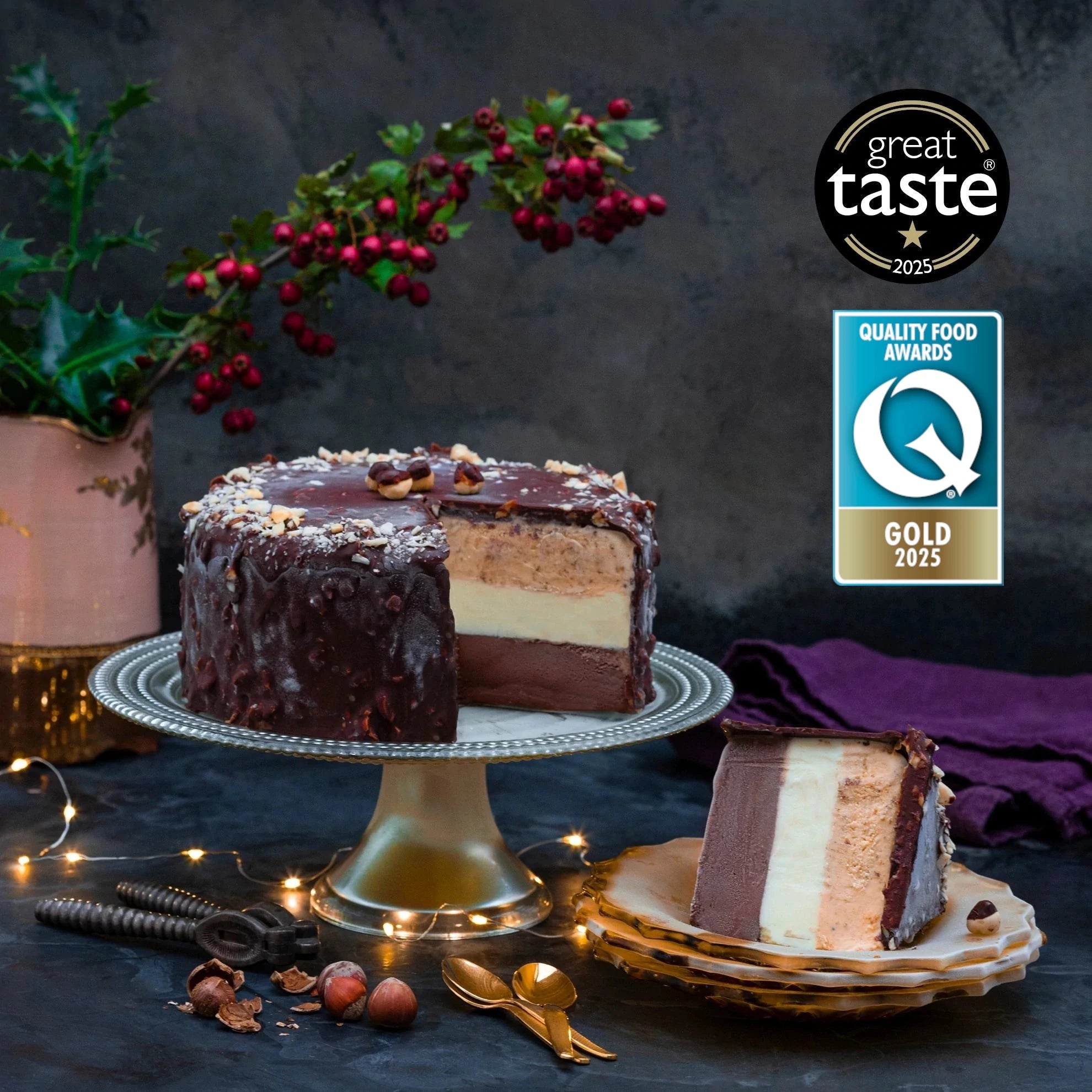 An ice cream cake coated in dark chocolate, cut through to reveal layers of different colours, against a festive background an two awards logos