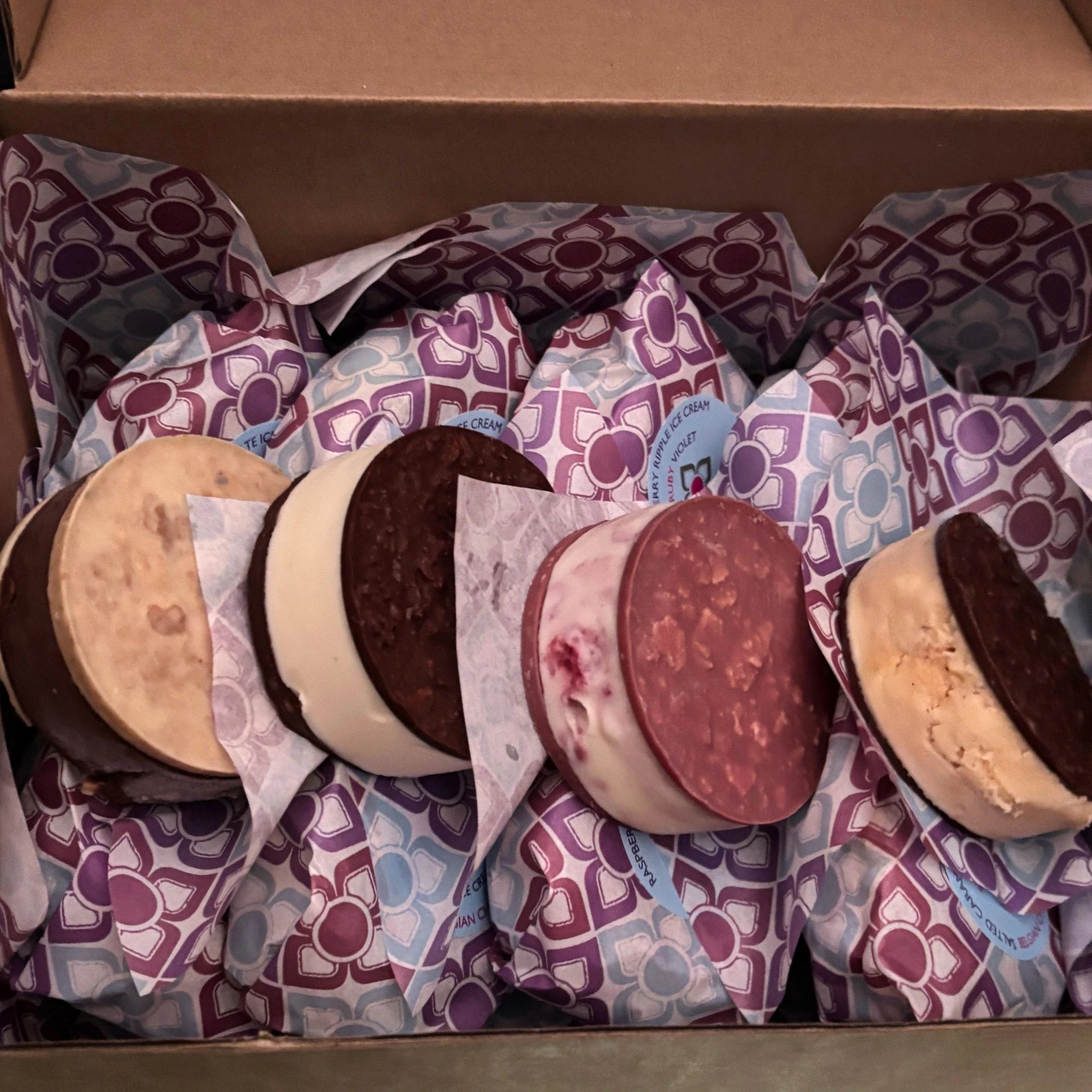 Ice cream sandwiches in patterned wrappers inside a cardboard box