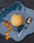 A scoop f pineapple sorbet on a plate with pieces of desiccated pineapple 