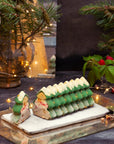 Christmas tree-shaped dessert on a marble slab with festive decorations in the background