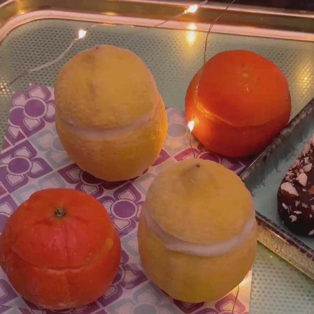 Frozen lemons and clementines, 6 little ice cream tubs piled on each other and 4 colourful ice creams on stick surrounded by fairy lights. 