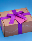 A Ruby Violet cardbord box closed with a purple satin ribbon and matching card