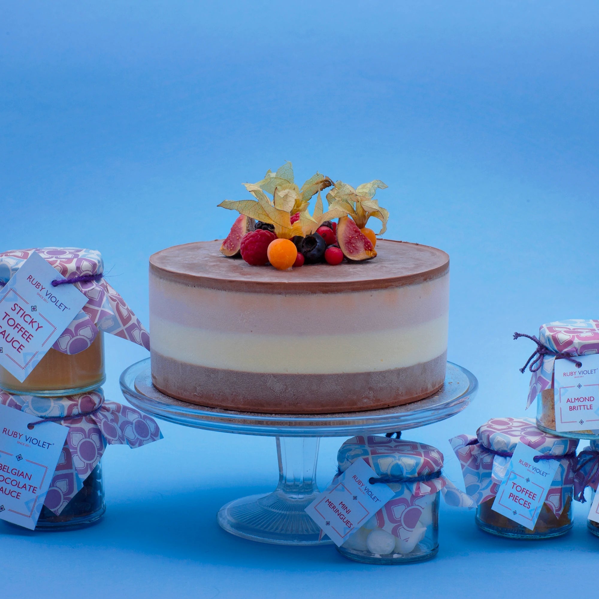 Miss Mabel ice cream cake decorated with fondant roses, with sauces and toppings in jars on the side