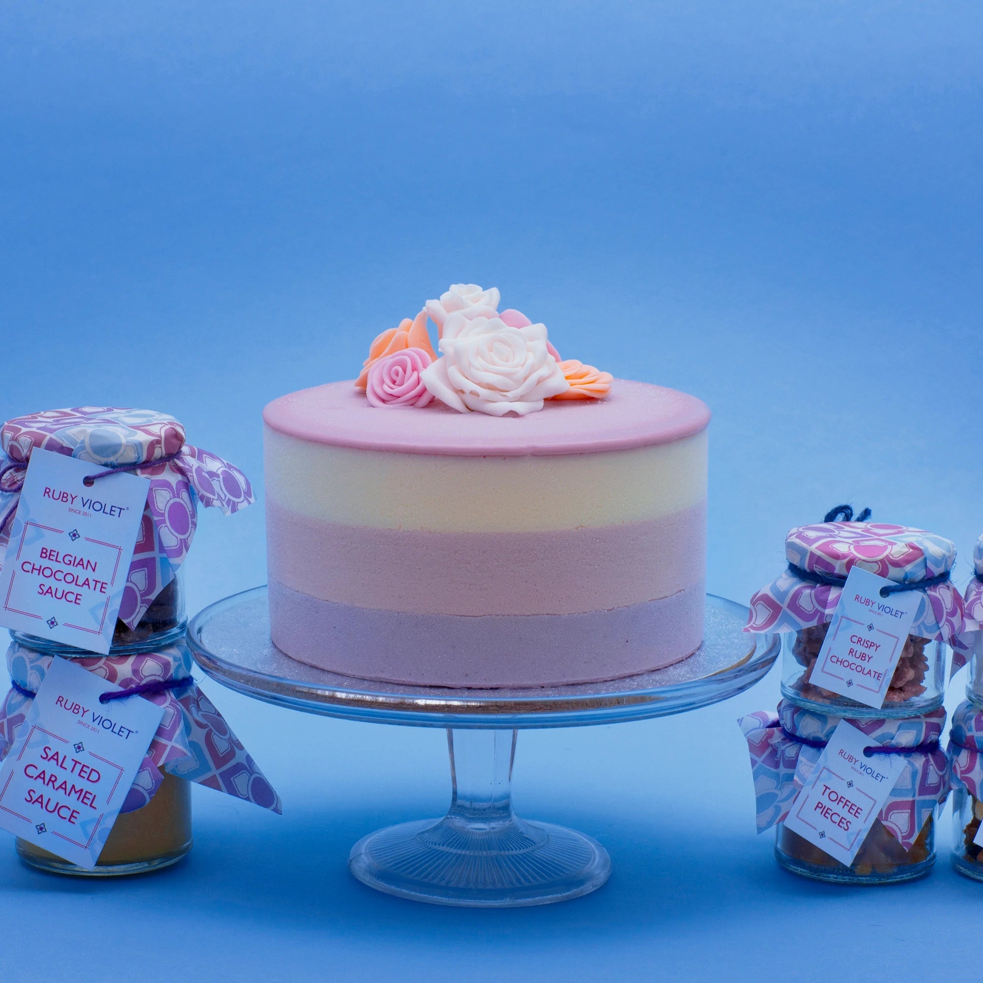 Miss Elodie ice cream cake decorated with fondant roses, with sauces and toppings in jars on the side