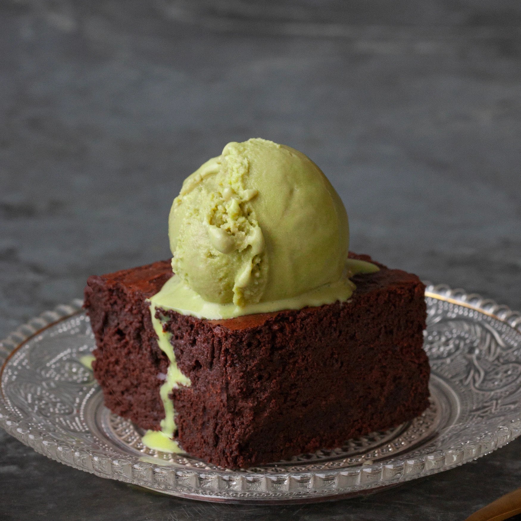 Chocolate brownie with a scoop of ice cream on a decorative plate against a dark background