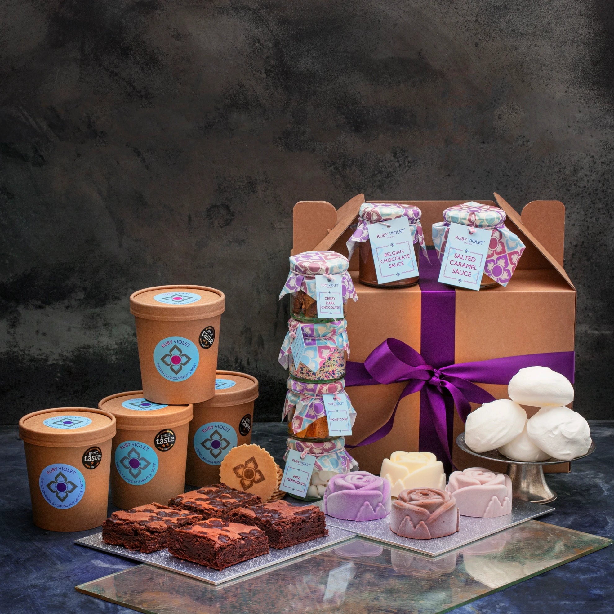 Assorted treats including ice cream, brownies,sauces and toppings and ice cream flowers with a hamper box wrapped with a purple ribbon