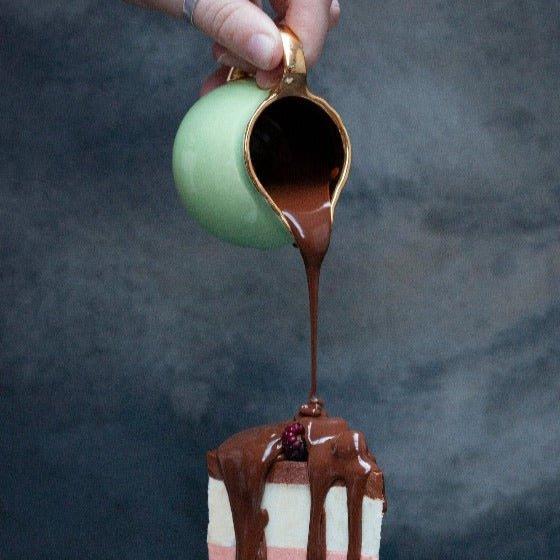 Belgian Chocolate sauce being poured over a slice of ice cream cake