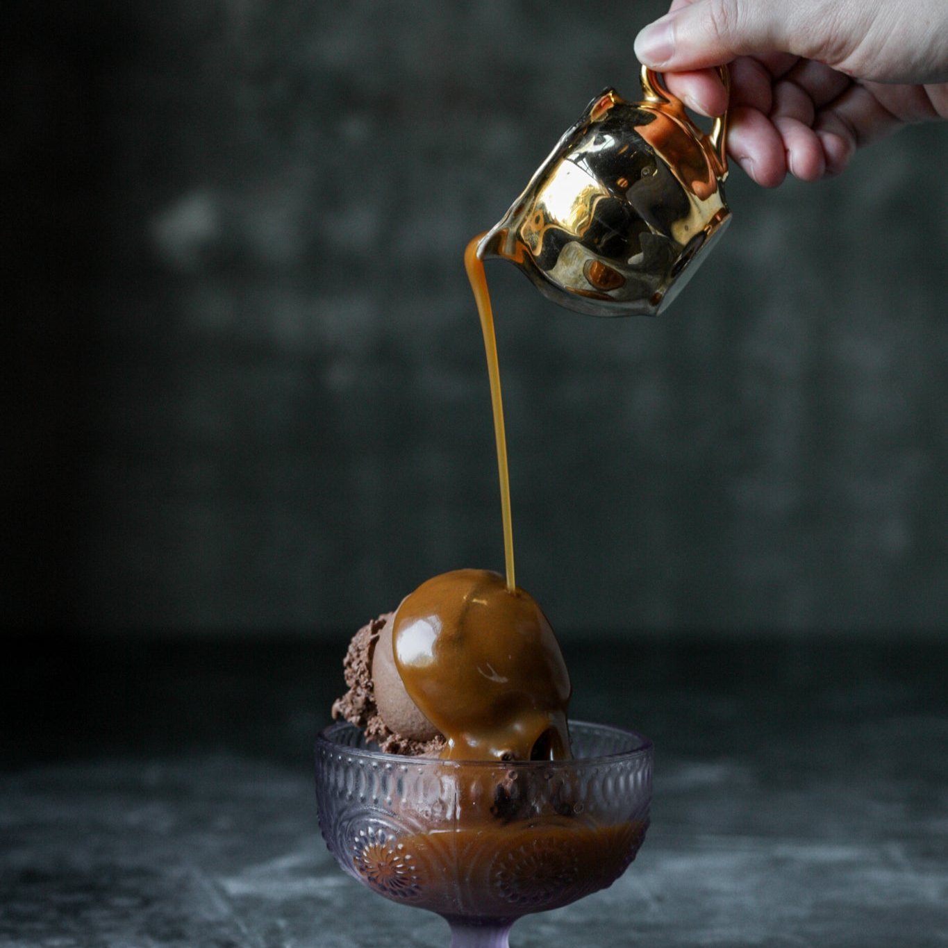 Maldon Salt caramel sauces being poured over a scoop of ice cream from a little golden jug