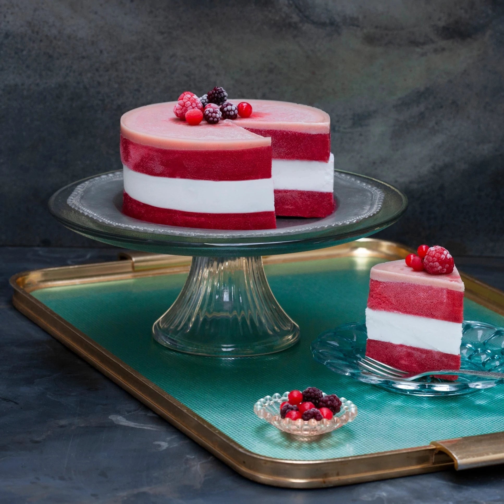 Handmade vegan raspberry and coconut cake on a cake stand with a slice cut out