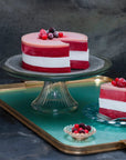 Handmade vegan raspberry and coconut cake on a cake stand with a slice cut out